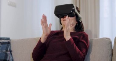 Mutlu ve gülümseyen yaşlı kadın sanal gerçeklik gözlüğü kullanırken, kanepede otururken o çok bu yeni teknoloji hakkında etkilendim