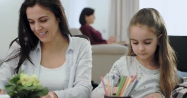 Mükemmel bir gülümseme ile olgun anne o çok mutlu ve heyecanlı bazı okul projesi yapmak için onu üç çocuk yardımcı olgun anne, çocuklar çok proje üzerinde konsantre ise büyükanne bir kitap okurken