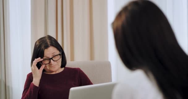 心理学者の老婆は、うつ病を持っているwomna患者の魔女とのセラピーセッションを持って、医師は非常に集中して聞いて、彼女のノートに何かを入力しています。4k — ストック動画