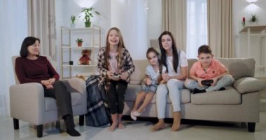 Konsantre ve heyecanlı bir video oyunu erkek ve kız kardeşi büyükanne ve anne onlara bakarak ve seviyeleri geçmek için destekleyen oynarken