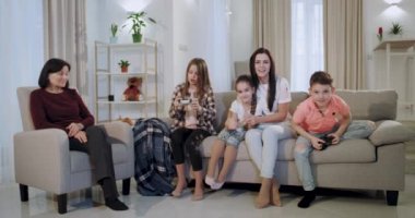 Komik gülümseyen anne ve çocukları o düzeyde geçerken o düzeyde geçerken bir video oyunu oynarken birlikte eğlenceli bir zaman var , o otururken torunları için eski büyükanne mutlu