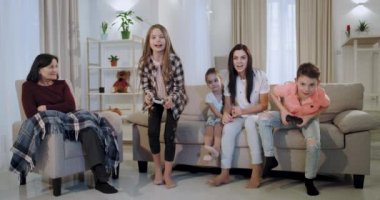Komik çocuklar erkek ve kız kardeşi bir video oyunu erkek kardeşi oynarken kazanan oldu, anne mutlu ve gülümseyerek oğlu sarılma ise kızı üzgün anneannesi onu teşvik , onlar kanepede oturan