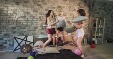 En iyi arkadaşlar genç bayanlar için komik zaman yastık ile dayak ve güzel bir pijama giyen modern yatak odasında bir yatıya gece partisi var