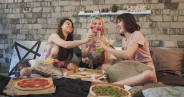Evde bir bayan için parti zamanı, pizza yemek ve bazı içecekler bir şişe içme harika hissediyorum, bir pijama giyen ve modern yatakta döşeme.