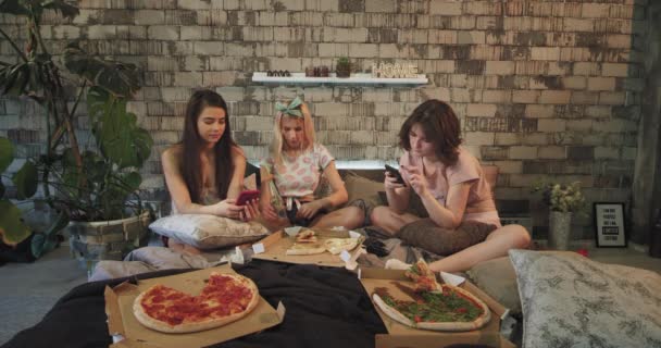 Home party teenager ladies enjoying the time in bedroom eating pizza chatting and using the smartphone to navigate on internet — Stock Video