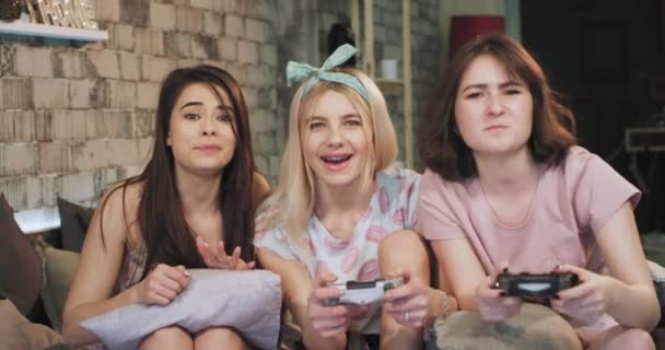 I en pyjamas damer har en Sleepover natt spendera en bra tid att spela på en PlayStation spel leende stora mycket karismatisk njuter av tiden — Stockvideo