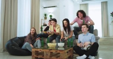 Çok komik ve mutlu arkadaşlar çekici birçok ırk bir video oyununda oynarken bazı bira içme ve çok heyecanlı bir oturma odasında çok aydınlık ve ferah oturan duygu,.. 4k