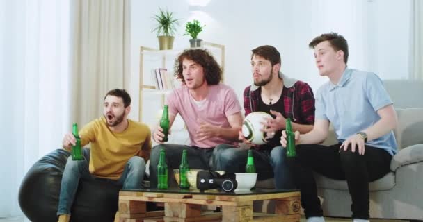 Gran compañía de hombres viendo un partido de fútbol están emocionados de que su equipo haga un gol que celebran frente a la televisión bebiendo cerveza y pasando un buen rato entusiasta — Vídeos de Stock