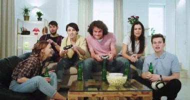 Tv'de bir video oyunu oynayan kanepebüyük çok etnik arkadaşlar iki tanesi bayan kazanan oldu adam kaybetti o tüm arkadaşlar onları destekleyen üzgündü