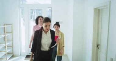 Olgun kadın profesyonel emlakçı bir ev turu yapmak genç bir aile çift için tüm iç modern tasarım gösterir çok onlar aracılığıyla bakarak ajan için bazı sorular vererek etkilendim