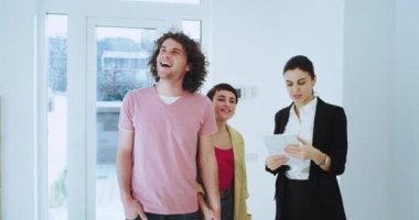 Genç bir aile cadı için yeni modern ev gösteren büyük bir gülümseme ile emlakçı çekici kadın bir tablet kullanarak ev planı ile bakarak çok etkilendim