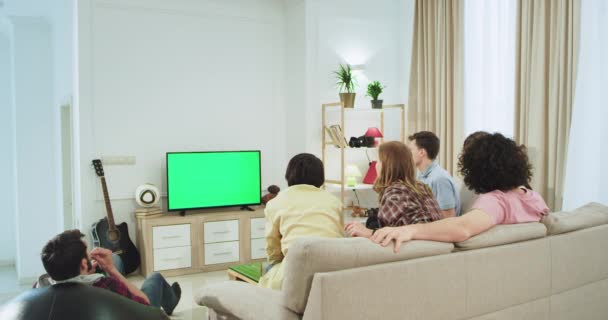 Zelená obrazovka v televizi velká skupina přátel na pohovce ve velkém prostorných obývacím pokoji, které sledují něco v televizi, multietničtí lidé spolu mají filmový čas.