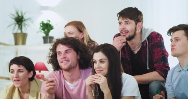 Uśmiechnięta i szczęśliwa skoncentrowana Grupa przyjaciół oglądając mecz piłki nożnej podekscytowany krzyczeć i okłoto z butelkami piwa, podczas gdy ich zespół wygrać mecz — Wideo stockowe