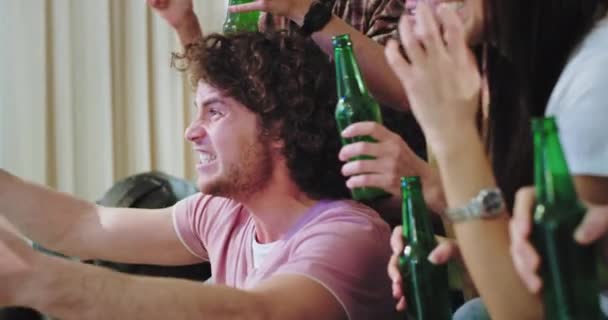 Portrait von erstaunlichen attraktiven Kerl mit lockigem Haar mit seinen Freunden multiethnischen feiern aufgeregten Sieg ihrer Fußballmannschaft schreit Jubel und klatscht in die Hände — Stockvideo
