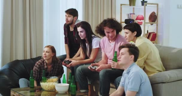 Em uma sala de estar uma grande empresa de amigos multi étnicos têm um tempo funt juntos em um jogo de vídeo Na frente da TV, todos os amigos se divertir e desfrutar juntos — Vídeo de Stock