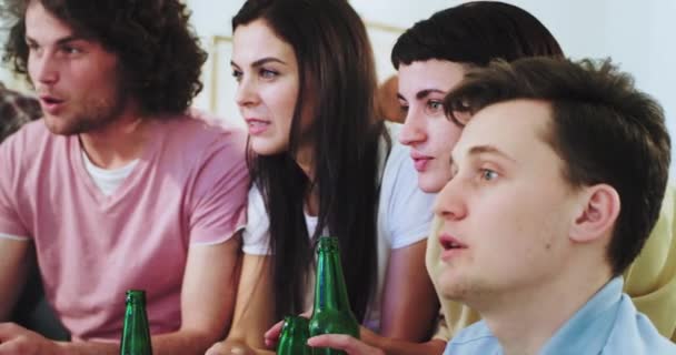 Портрет с концентрированными и артистичными друзьями, смотрящими футбольный матч перед телевизором, они празднуют цель своей команды многонациональными и увлеченными людьми — стоковое видео