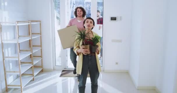 En una espaciosa casa carismática pareja y sus amigos tienen un día conmovedor felices y emocionados llevando las cajas y muy impresionados analizando el diseño de la casa — Vídeo de stock