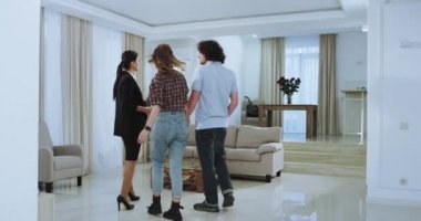 Geniş bir büyük evde genç evli çift ve müşteri için yeni evi temsil eden çekici emlakçı onlar çok heyecanlı ve etkilendim