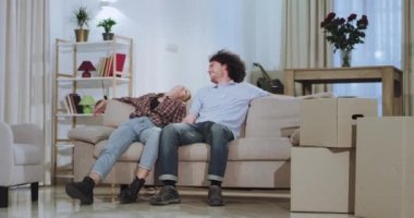 Onlar zor bir taşıma gününden sonra yeni bir evde hareket ederken zaman zevk Çekici güzel çift onlar kanepeye oturup tv izlerken