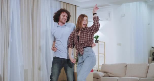 Pareja carismática y divertida después de un duro día de mudanza en una nueva casa que dacing y sentirse feliz en un nuevo apartamento — Vídeos de Stock