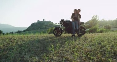 Motosiklet üzerinde oturan güzel çift doğanın manzara manzarasının tadını çıkarmak için durdu, birbirlerine sarılma ve birlikte güzel hız zaman
