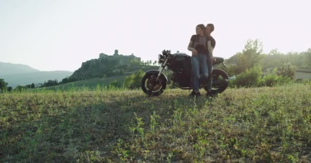 Όμορφο ζευγάρι που κάθεται στη μοτοσικλέτα σταμάτησε να απολαμβάνει το τοπίο θέα της φύσης, αγκαλιάζοντας ο ένας τον άλλο και υπέροχο χρόνο ταχύτητας μαζί — Αρχείο Βίντεο