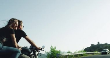 Young couple spending romantic time together on the motorcycle big Bugatti monster in the middle of the motorway with amazing landscape.