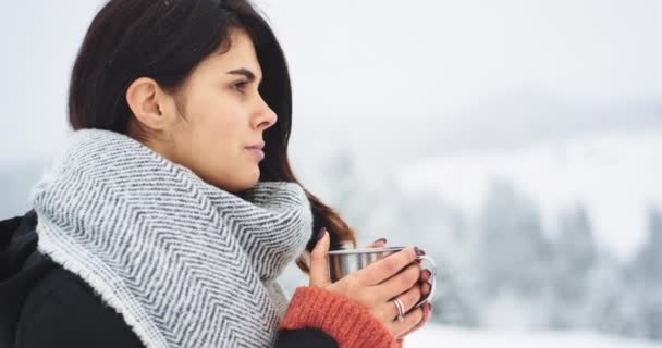 Congelamento donna beve un po 'di tè caldo in mezzo alla montagna, in una giornata di congelamento con neve giovane donna bere qualche bevanda calda da tazza di ferro . — Video Stock