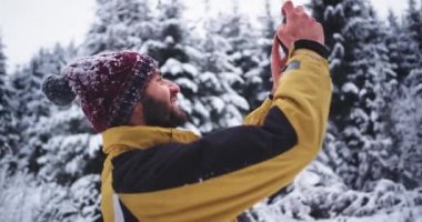 Young tourist taking pictures of a snowy forest in the winter day , he are very impressed by the all beauty he see around him