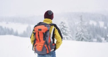 Karlı ormanda yürüyüş turist tüm seyahat şeyler ile donatılmış , büyük bir turuncu çanta ile , o dağın ortasında seyahat