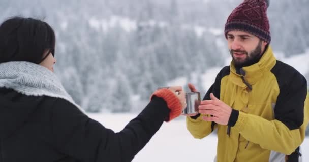 Dos buenos amigos mujer y hombre beben té caliente para calentarse en medio del bosque nevado, beben feliz — Vídeo de stock