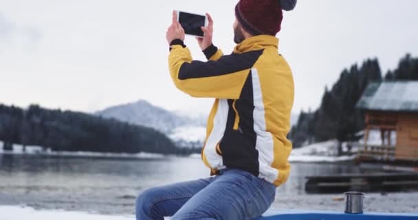 Capturando foto usando um tablet um jovem turista muito exaltado de lugar, ele sentado em um barco azul na margem do lago e admirar toda a beleza da natureza, e tirar algumas memórias para si mesmo — Vídeo de Stock