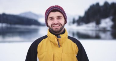 Kamera önünde gülümseyen büyük adam Portresi , göl ve karlı orman ve dağ inanılmaz arka plan ile manzara ortasında, o kırmızı bir burun ve karizmatik yüzü var