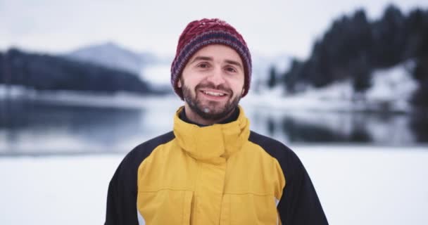 Ευτυχισμένοι τουρίστες έχουν παγώσει έξω, στέκεται κοντινό στο φόντο της κάμερας μεγάλη λίμνη και χιονισμένο δάσος και βουνό, δείχνει ένα μεγάλο όπως μπροστά από την κάμερα — Αρχείο Βίντεο