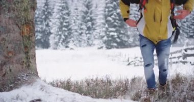 Genç turist, karlı ağacın altında mola vermek için durdu. Turuncu çantasını çıkardı ve dağın ortasındaki ağaca koydu.