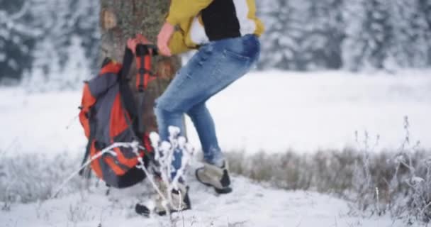 Turysta w środku góry obok ośnieżonym lesie wziąć swoją wielką pomarańczową torbę i kontynuować swoją przygodę do zwiedzania miejsca wokół — Wideo stockowe