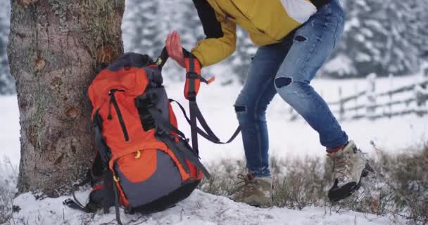 Close-up toeristen nemen van beneden zijn oranje tas en beginnen wandelen door het besneeuwde veld naar zijn volgende bestemming — Stockvideo