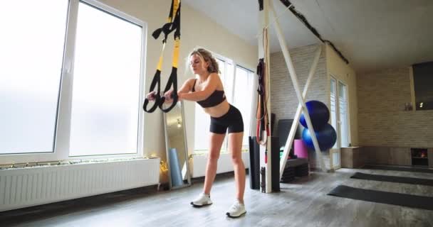 Piękna Blondynka Pani praktykujących całkowitą odporność ciała ćwiczenia TRX do szkolenia jej smukłe i ciało mięśni koncepcji stylu życia w nowoczesnym Studio aerobik Wellness — Wideo stockowe