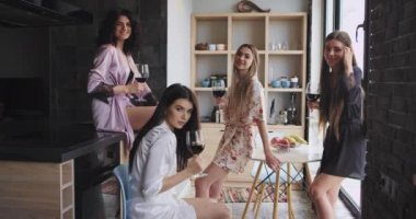 Şaşırtıcı şık pijama çok etnik bayanlar şarap bardak tutan ve kameraya bakarak modern bir daire tasarımı birlikte zaman keyfini çıkarın.