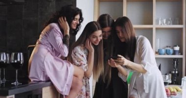 Çekici gülümseme ile iyi görünümlü bayanlar evde pijama bir bekarlığa veda partisi var onlar büyük gülümseyerek ve inanılmaz loft tasarım stüdyosunda bir akıllı telefon ile bakıyor