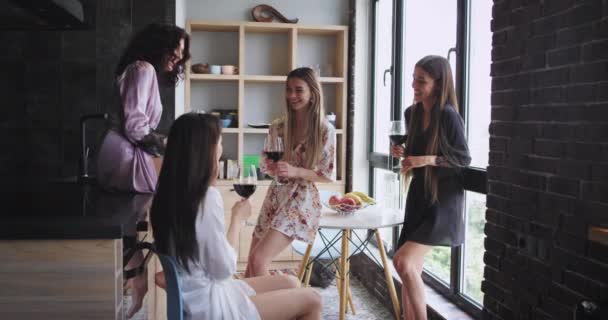 Multi senhoras étnicas em pijama aproveitando o tempo juntos enquanto bebem vinho em um estilo urbano de design loft panorâmico eles estão muito animados — Vídeo de Stock