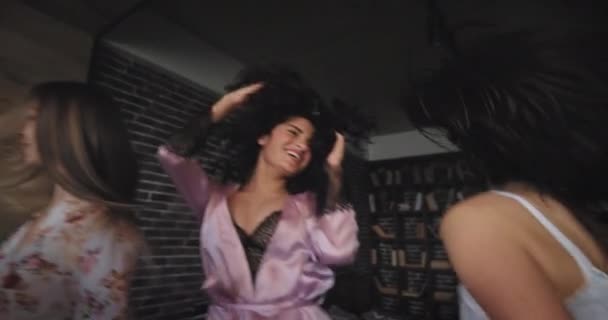 Прыгающая группа из четырех дам танцующих и взволнованных дома в пижаме они празднуют девичник улыбаясь большой в городской квартире студии дизайна — стоковое видео