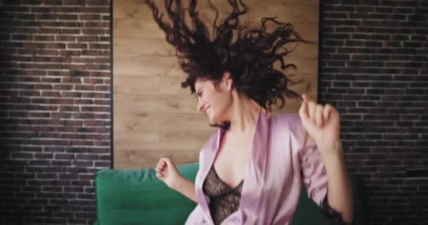 Mulher cabelo encaracolado impressionante em um pijama sexy dançando louco na frente da câmera em seu apartamento estúdio moderno ela sorrindo grande tem um ótimo humor pela manhã — Vídeo de Stock