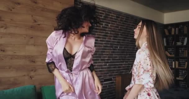 Uzun saçlı bayan ve onu kıvırcık saçlı arkadaşlar ile birlikte zaman zevk pijama kamera önünde sabah atlama ve dans — Stok video