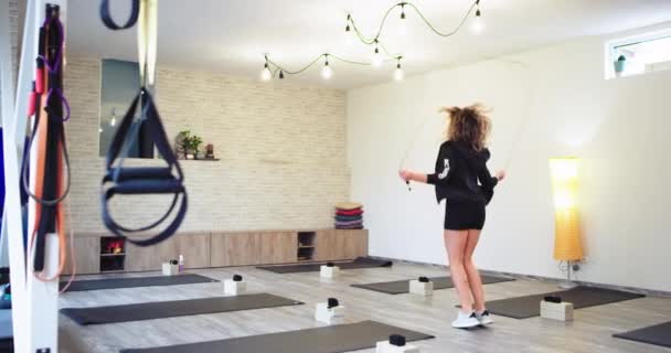 Krullend blonde dame in een wellness studio springen op een het touw nemen video van de back Health lifestyle concept — Stockvideo