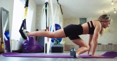Olgun bayan o çok spor pratik konsantre büyük bir geniş aerobik stüdyoda vücut ve bacaklar germe Trx kayışları pratik