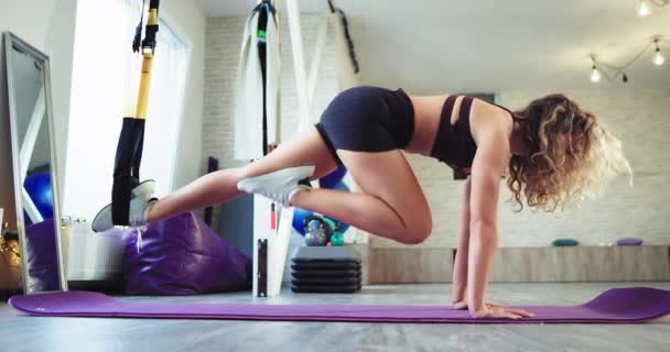 Hartes Konzept einer Stretching-Körperübungen mit einem Riemen Trx Gummibänder Dame übt Aerobic in einem geräumigen Studio — Stockvideo