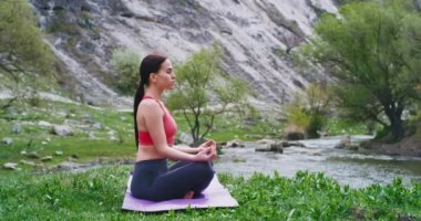 Yoga büyük nehir görünümü önünde güzel manzara ortasında minderin üzerinde genç bir bayan meditasyon pratik pozlar