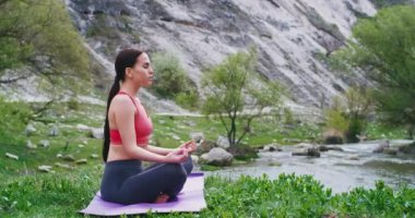 Manzara yoga yoga ile doğanın ortasında paspas üzerinde güzel genç kadın o bir meditasyon kapalı gözleri ile pozlar önünde güzel nehir ile doğada temiz bir hava almak