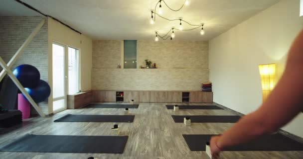 Moderna signora studio di yoga in arrivo per iniziare la sua meditazione yoga tenendo sulle mani il suo tappeto sportivo e indossando un abbigliamento sportivo — Video Stock